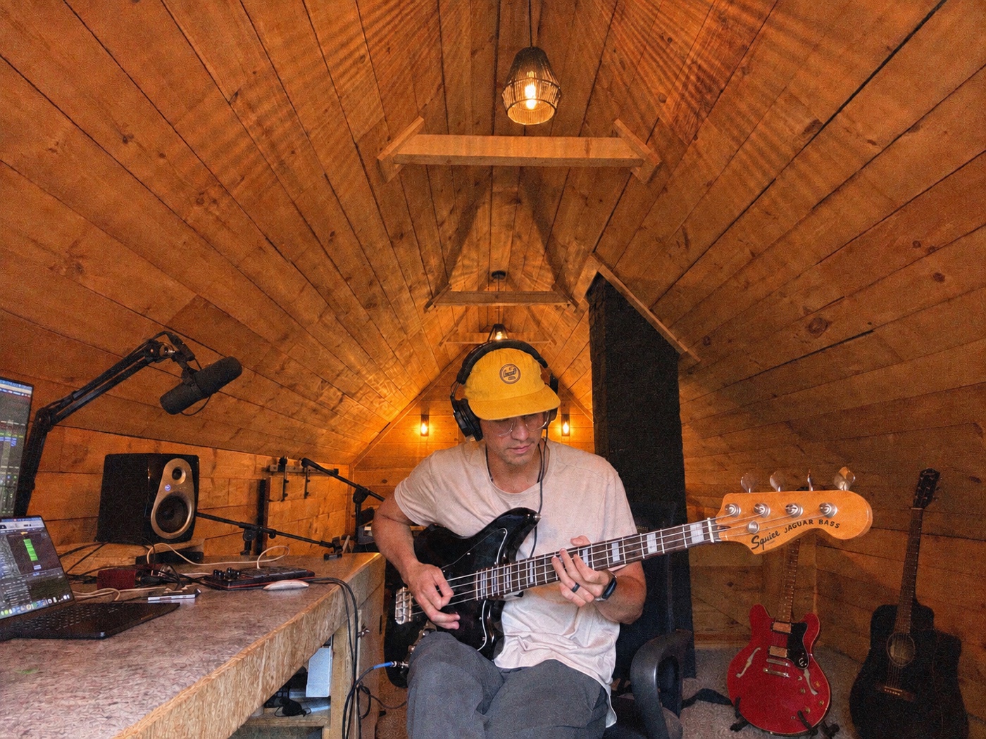 sam playing bass in a warmly lit, wood-paneled recording studio